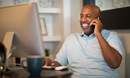 Happy man on the phone in front of his computer